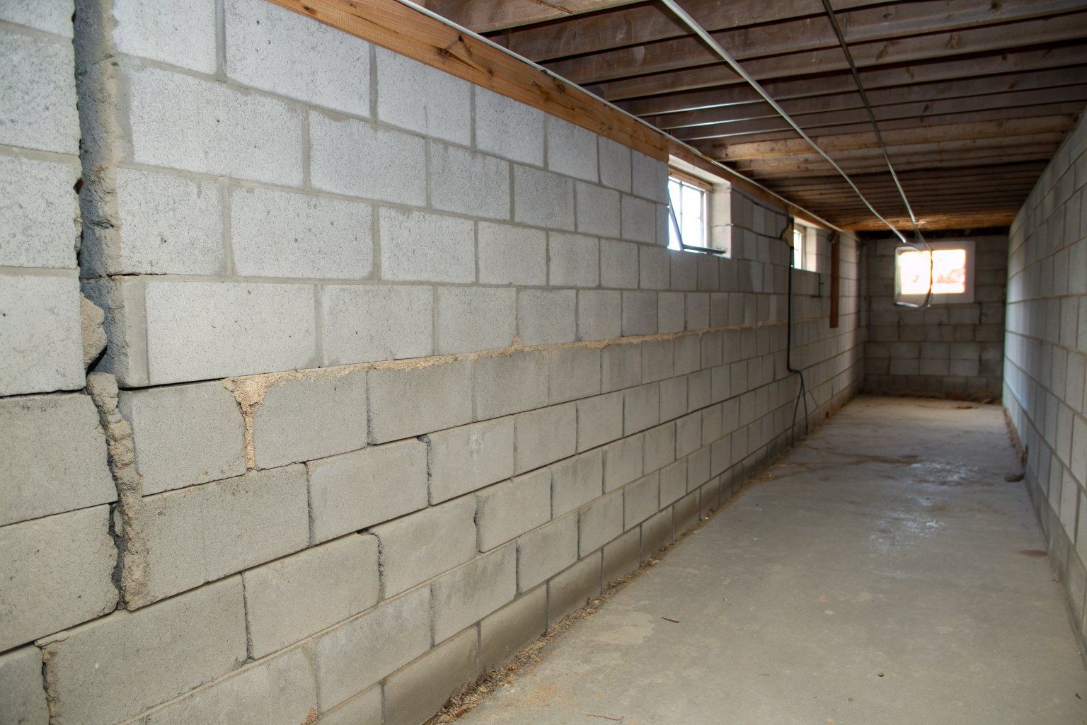 Gray concrete block wall with a long horizontal crack along a mortar joint